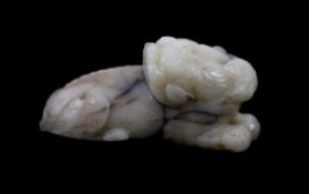 A Chinese Ming white and black jade figure of a recumbent beast,biting a sprig of lingzhi fungus