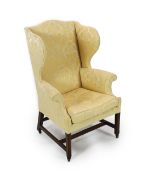 A George III mahogany wing armchair,with golden foliate fabric upholstery and H stretcher, on