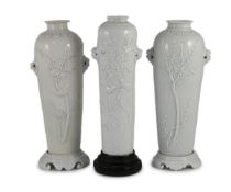 A near pair of Chinese blanc-de-chine sleeve vases with stands and a similar slender vase, Dehua