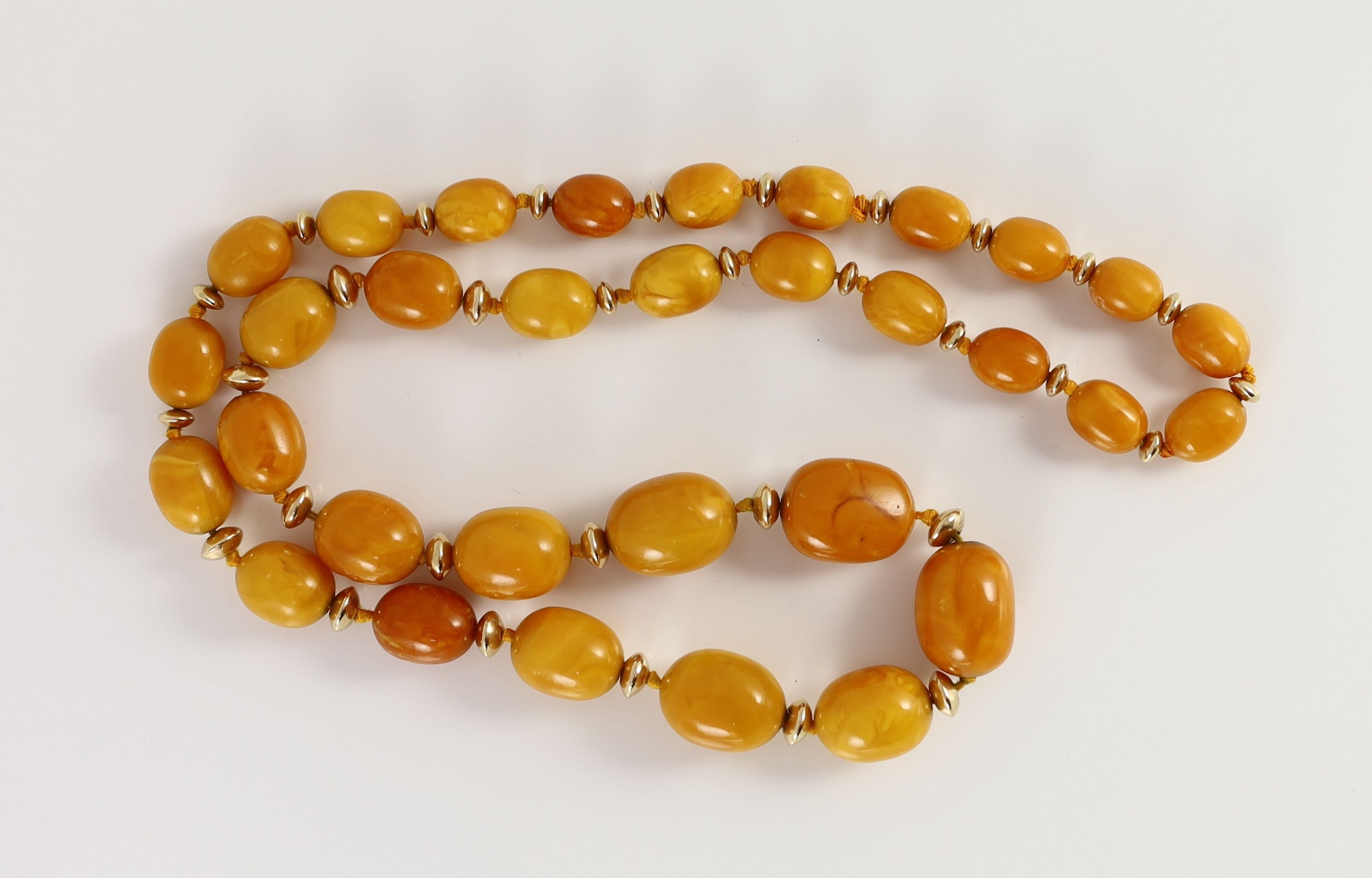 A single strand graduated oval amber bead necklace, with gilt metal spacers, 80cm, gross weight 92 - Image 2 of 2