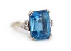 A modern 18ct white gold and emerald cut blue topaz set dress ring,with six stone diamond set