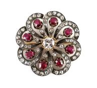 A late Victorian gold and silver, ruby and diamond set whorl shaped brooch,the central stone