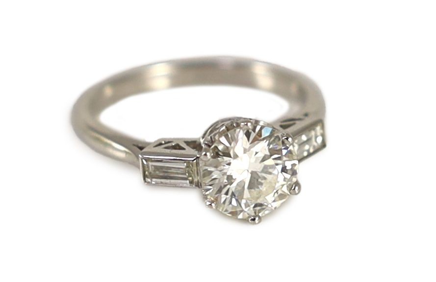 A platinum and single stone diamond ring, with baguette cut diamond set shoulders,the central