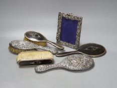 A George V silver and tortoiseshell mounted brush set and a tow similar embossed silver items(a.