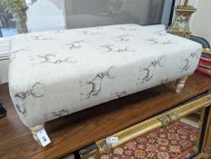 A large contemporary rectangular footstool / coffee table upholstered in stag print fabric on turned