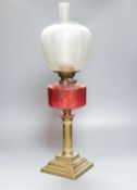 A brass and cranberry glass oil lamp with shade and chimney, total height 66cm
