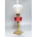 A brass and cranberry glass oil lamp with shade and chimney, total height 66cm