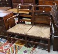 A George III provincial mahogany rush seat chair back settee, length 118cm, depth 53cm, height