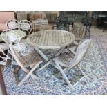 A weathered teak circular folding garden table, diameter 110cm, height 74cm and four folding chairs