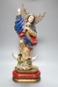A painted South American angelic figure, standing on a dragon on a crescent moon 49cm