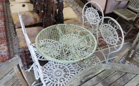 A wrought iron circular garden table, diameter 65cm, height 74cm and four folding chairs