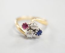 An early 20th century 18ct & plat, ruby, sapphire and diamond set four stone crossover ring, size M,