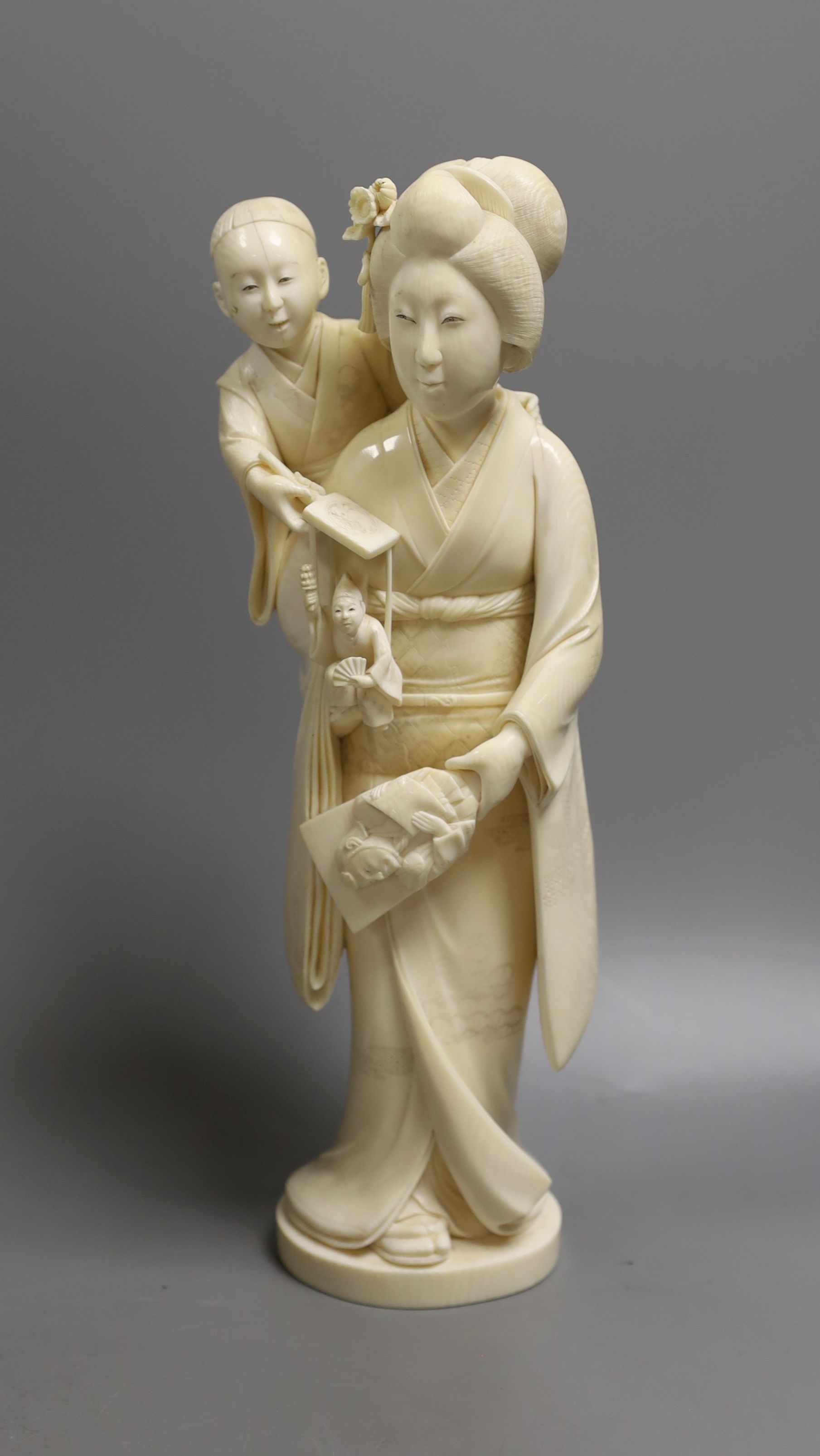 A large Japanese Tokyo School ivory okimono of a lady with child holding a puppet, Meiji period,