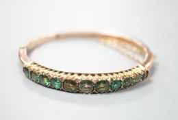 An Edwardian 9ct and graduated eleven green stone doublet set hinged bracelet, interior diameter