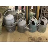 Four galvanised watering cans and a bucket