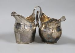 Two George III silver helmet shaped cream jugs, London, 1789 and London, 1796, tallest 10.6cm, 6.