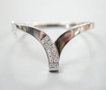 A modern 585 white metal and twelve stone diamond set wishbone shaped hinged bangle, gross 19.7