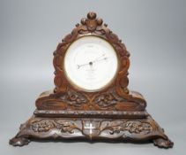 A late Victorian carved walnut aneroid mantel barometer by Negretti and Zambra,34 cms wide