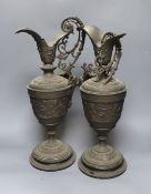 A pair of bronzed metal classical pedestal urns with scroll decoration and satyr masks (one handle