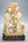 A Chinese soapstone carving of two ladies, wood stand, early 20th century36 cms high.