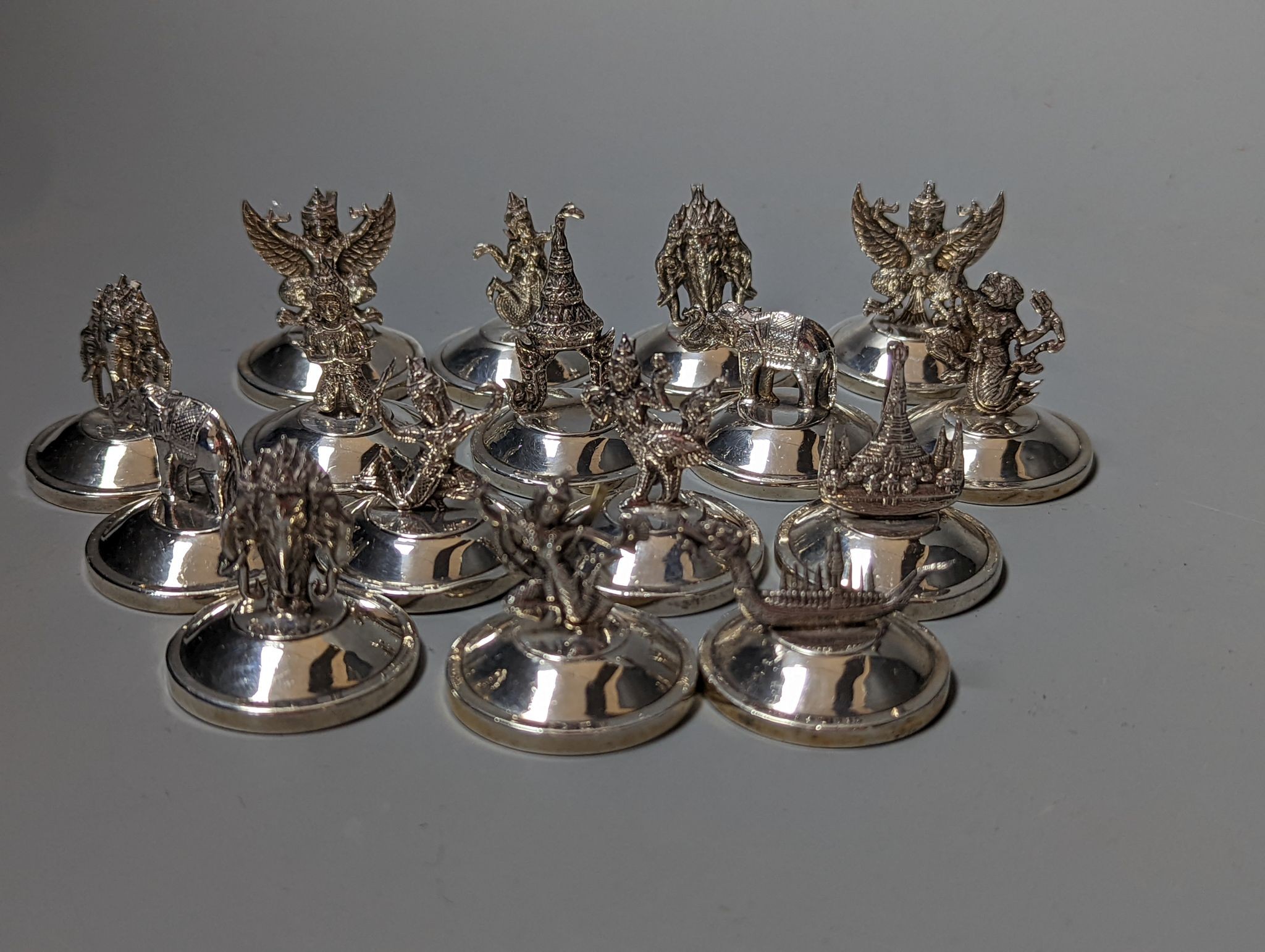 Sixteen assorted Siamese sterling mounted menu holders, modelled with figures, elephant, etc.