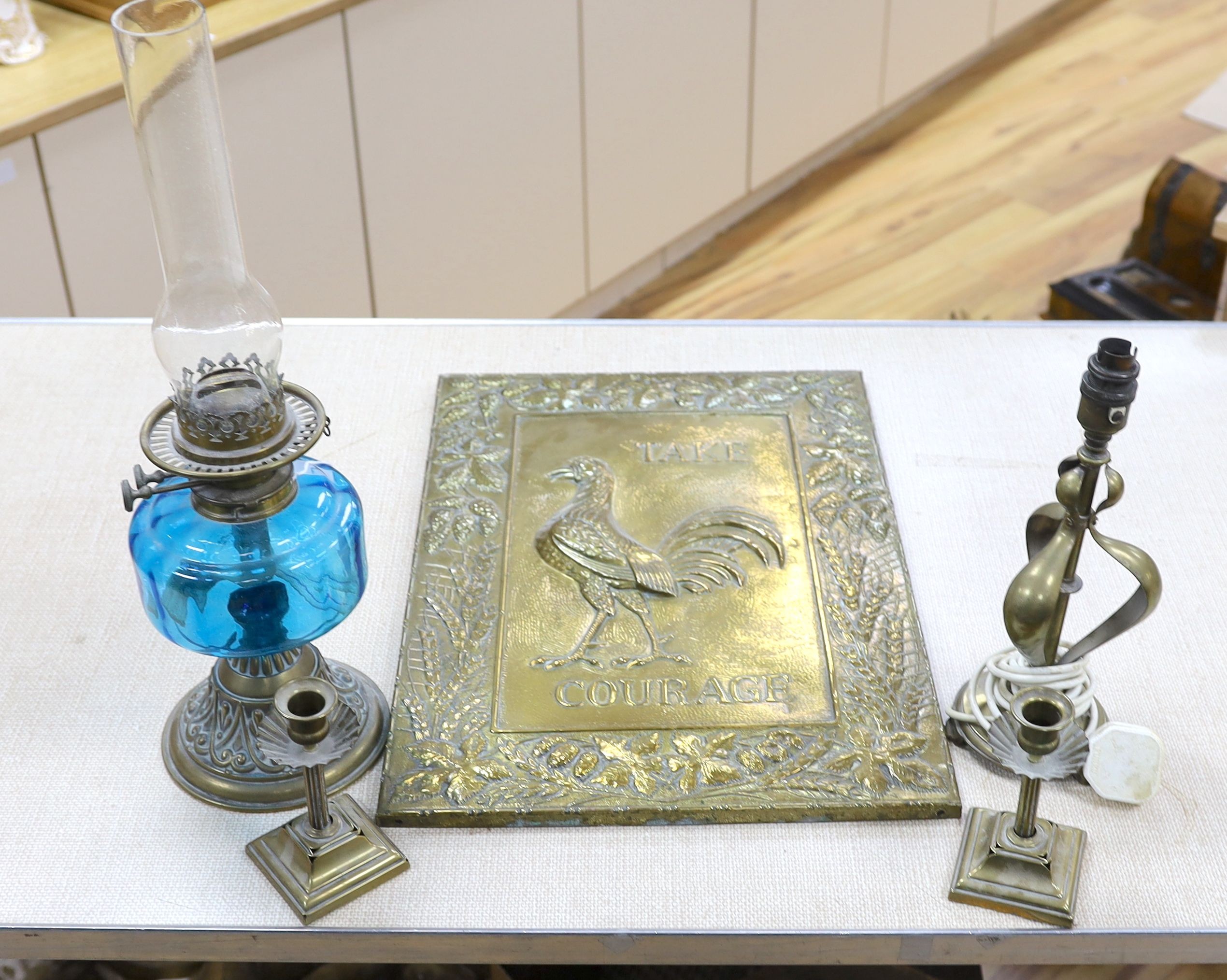 A brass Art Nouveau lamp, a pair of candlesticks, oil lamp and brass Courage advertising sign