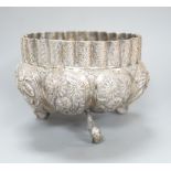 An Indian embossed white metal bowl, on three dolphin feet, diameter 13cm, 10oz.