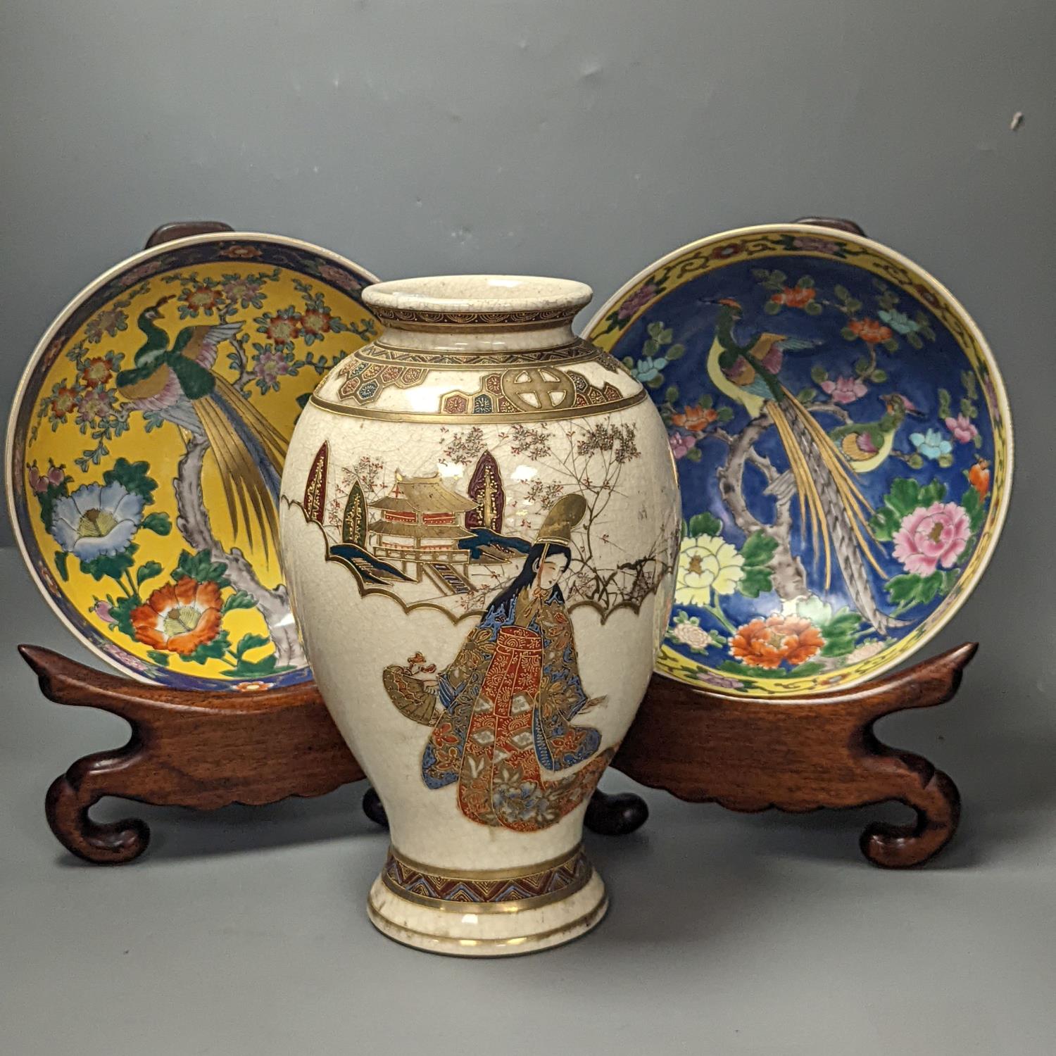 A Japanese Satsuma vase of a geisha and two Japanese yellow and a blue ground bowls each on wooden