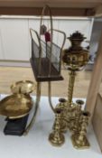 A brass magazine stand, a pair of scales, four candlesticks and a tall brass oil lamp base,Oil