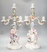 A pair of late 19th century German floral encrusted, figurative porcelain candelabra, 52 cms high.