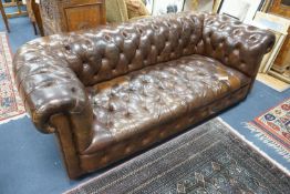 An early 20th century Chesterfield settee upholstered in deep buttoned brown leather, length