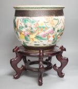 A Chinese famille rose ‘warriors’ jardiniere, late 19th century, wooden stand, 42 cms high including