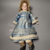 A German bisque headed doll, wearing a blue silk dress and straw bonnet, 42 cms high.