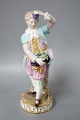 A 19th century Meissen figure of a boy holding grapes to his head, his hat full of grapes, wearing a