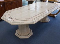 A Travertine marble dining table of elongated octagonal form on twin octagonal column supports,