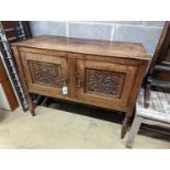 An early 20th century Arts & Crafts oak two door cabinet, carved with oak branches, width 100cm,