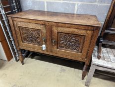 An early 20th century Arts & Crafts oak two door cabinet, carved with oak branches, width 100cm,