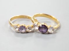 Two yellow metal and synthetic colour change corundum set three stone rings, one with zircons?,