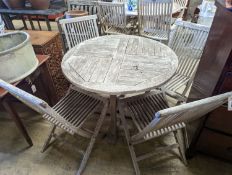 A circular weathered teak garden table, diameter 100cm, height 75cm together with four folding