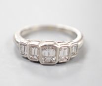 A modern platinum and graduated emerald cut five stone diamond set half hoop ring, size L, gross