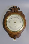 A late Victorian carved oak cased aneroid barometer and thermometer by Dollond, London, numbered