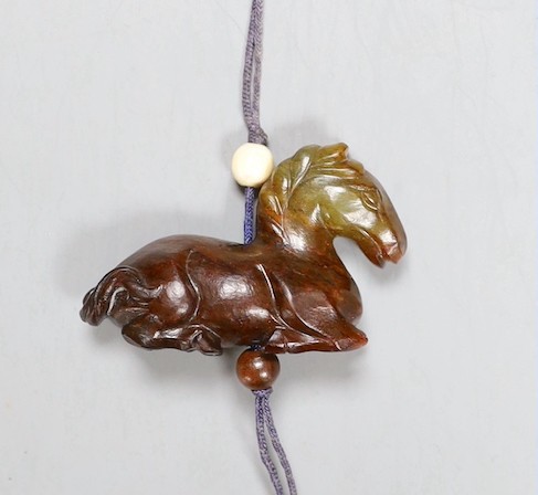 A Chinese green and brown jade ‘horse’ toggle. 4.5cm