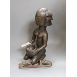 An African tribal carved wood kneeling figure holding bowl (44cm high) and tribal hand instrument (