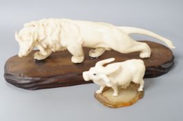 A Japanese ivory group of a lion grasping a hare in its mouth, wood stand, Meiji period, together
