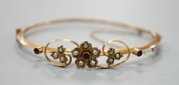 An Edwardian 9ct, red stone and seed pearl set hinged bangle, interior diameter 55mm, gross weight