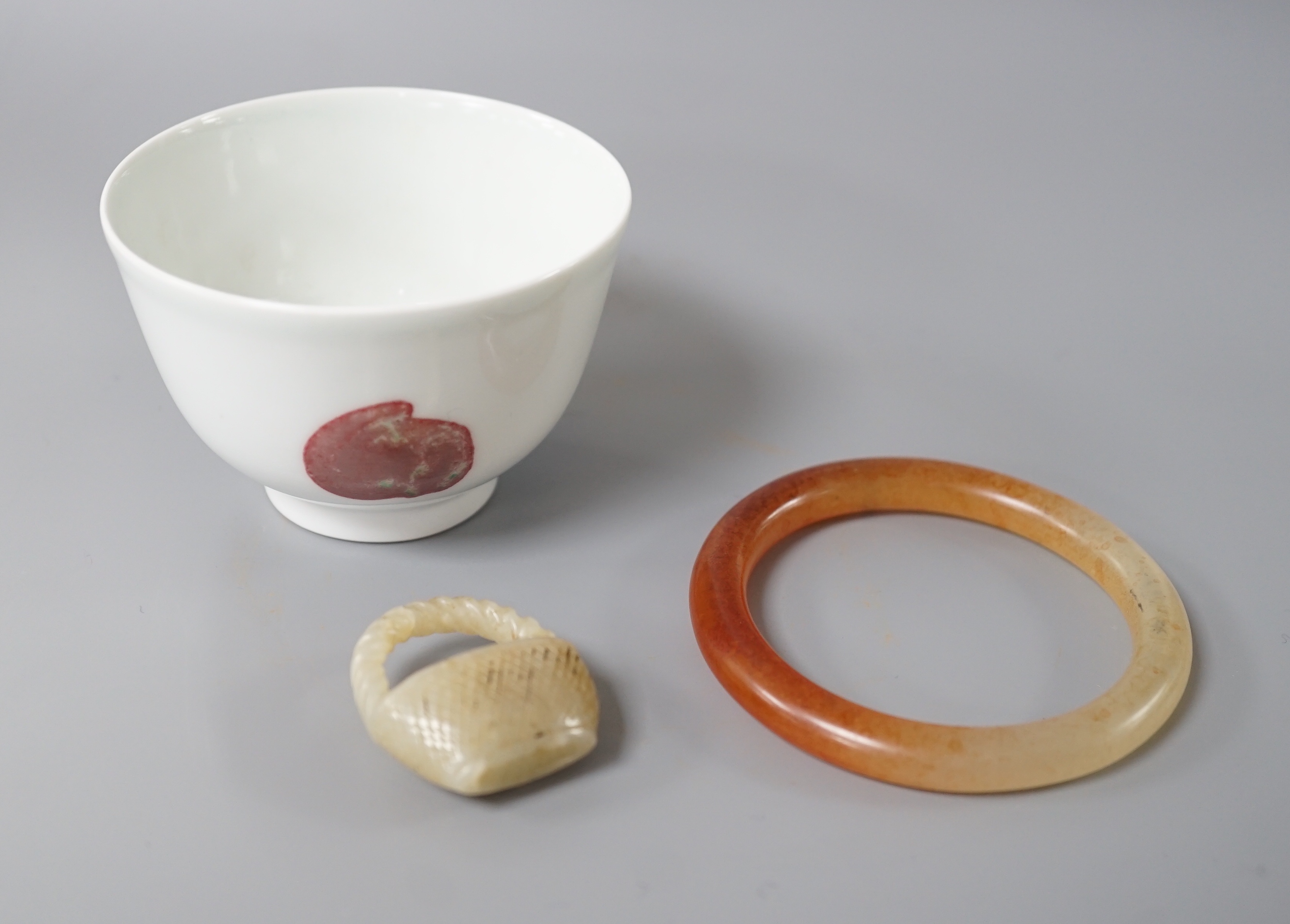 A Chinese porcelain teabowl with ‘fruit’ decoration, an agate bangle and a similar ‘basket’
