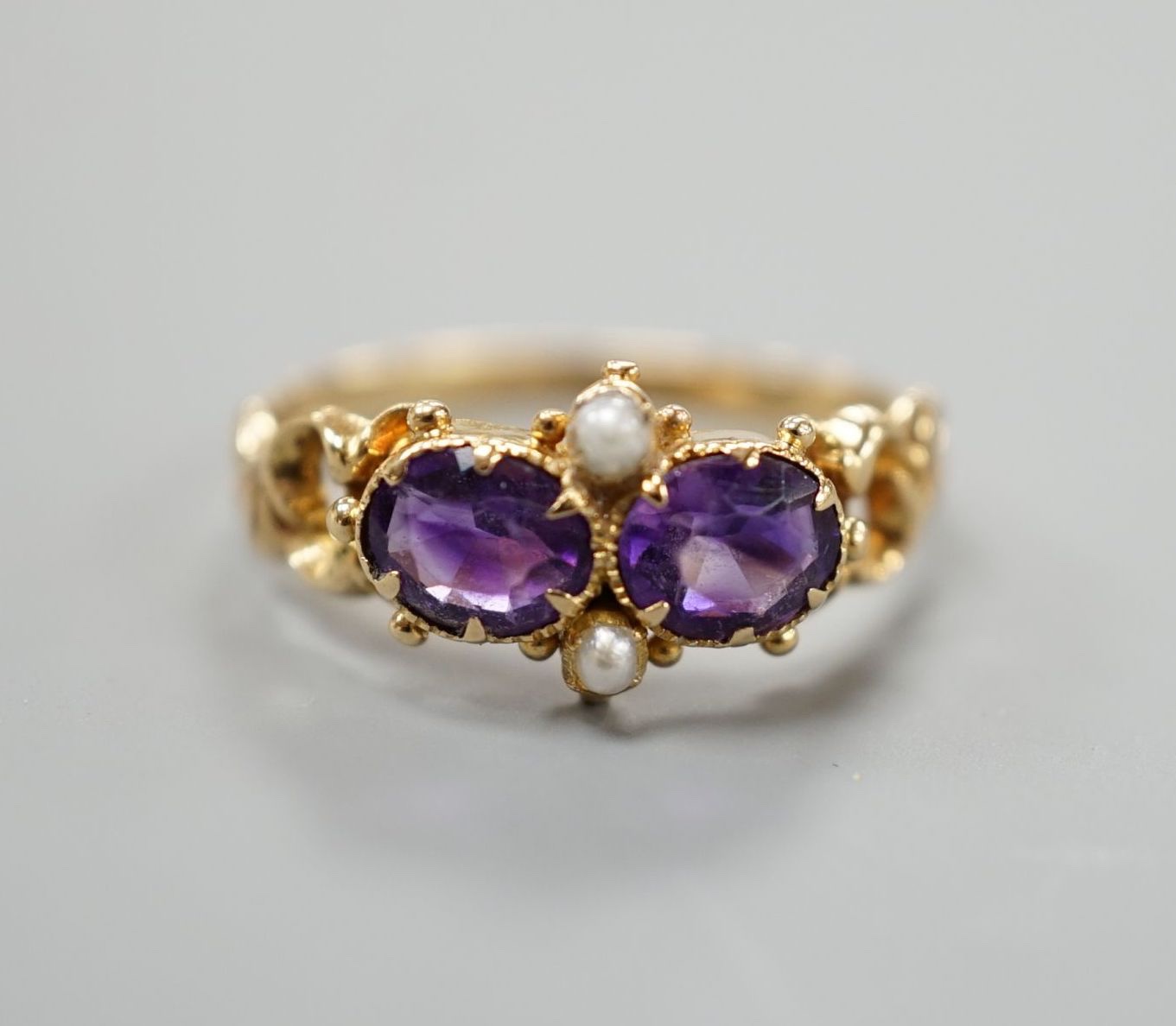 A late Victorian yellow metal, two stone amethyst and two stone seed pearl set cluster ring, size L,