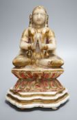 A late 19th century Indian carved alabaster seated figure, on associated wooden stand, 26cm