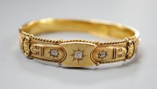 An Edwardian 15ct gold and three stone diamond set hinged bangle, interior diameter 57mm, gross