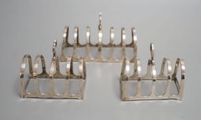 A matched suite of three silver toastracks, pair by Adie Bros. Birmingham, 1934 and larger by